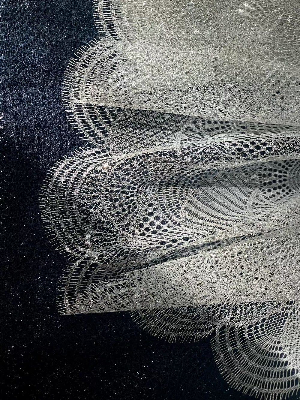 Détail de dentelle française aux motifs ajourés, utilisée dans les créations de LYSANDRE PARIS.